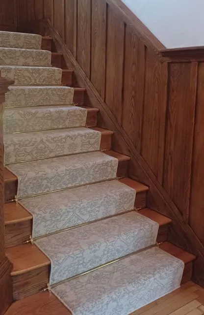 Brocade carpet and paneled walls over basement staircase